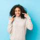 young-african-american-curly-hair-woman-smiles-pointing-fingers-mouth